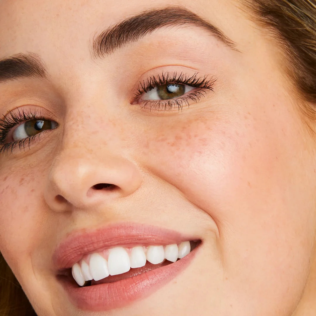 Close-up of a smiling model wearing jane iredale Lash Fixation mascara with defined upper lashes.