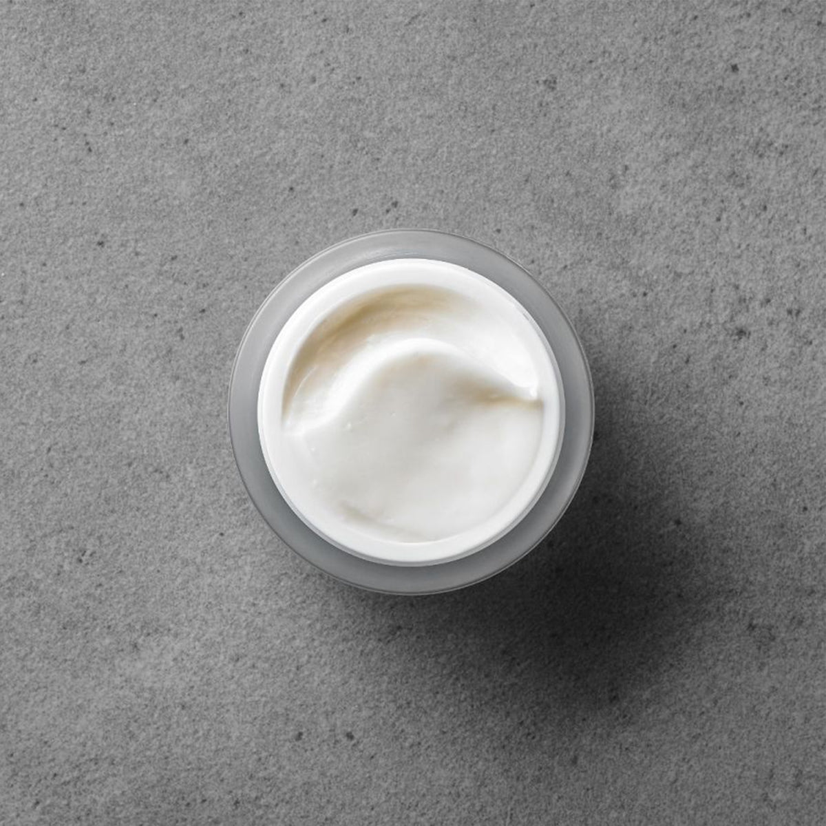 Jar of white cream on a gray surface