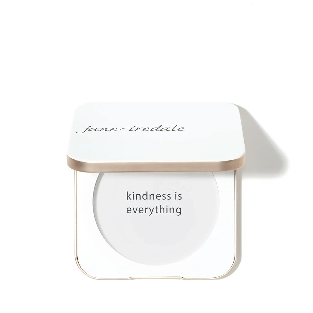 Open white jane iredale refillable compact with a gold-toned rim and the words kindness is everything inside the empty base.
