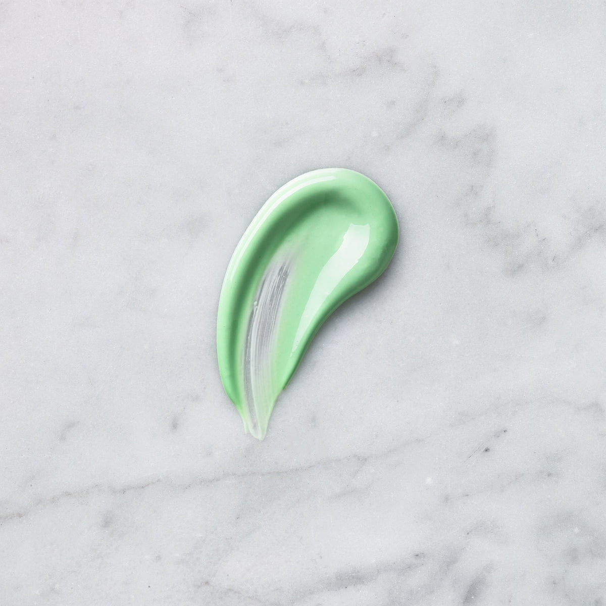 Green Medik8 Calmwise Colour Correct moisturiser swatch on a pale marble surface.