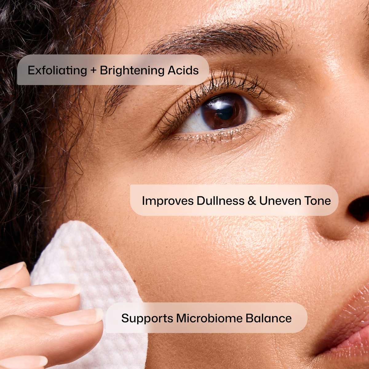 Close-up of a model using Revision Skincare Tone+ Correcting Pads, with captions describing acids, botanicals and postbiotic technology.